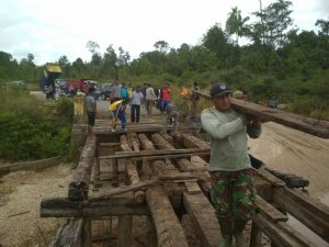 Tampak Anggota TNI AD dari Koramil 03/Sedanau, tengah memikul kayu untuk memperbaiki jembatan.