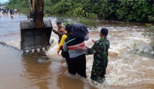 Tampak Anggota TNI AD bersama Masyarakat sedang membantu mengevakuasi warga yang terjebak banjir.