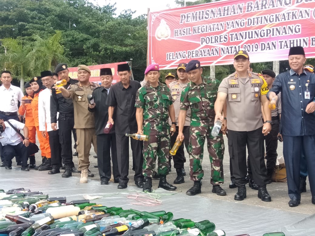 Kapolres Tanjungpinang AKBP M Iqbal, Wali Kota Tanjungpinang Syahrul, dan Unsur FKPD terlihat ikut membantu memusnahkan ratusan botol miras berbagai jenis merek, dari hasil kegiatan yang ditingkatkan (HKYD) jelang perayaan Natal 2019 dan tahun baru 2020, Kamis (19/12). Pemusnahan dilakukan di Lapangan Pamedan Ahmad Yani, Kota Tanjungpinang.